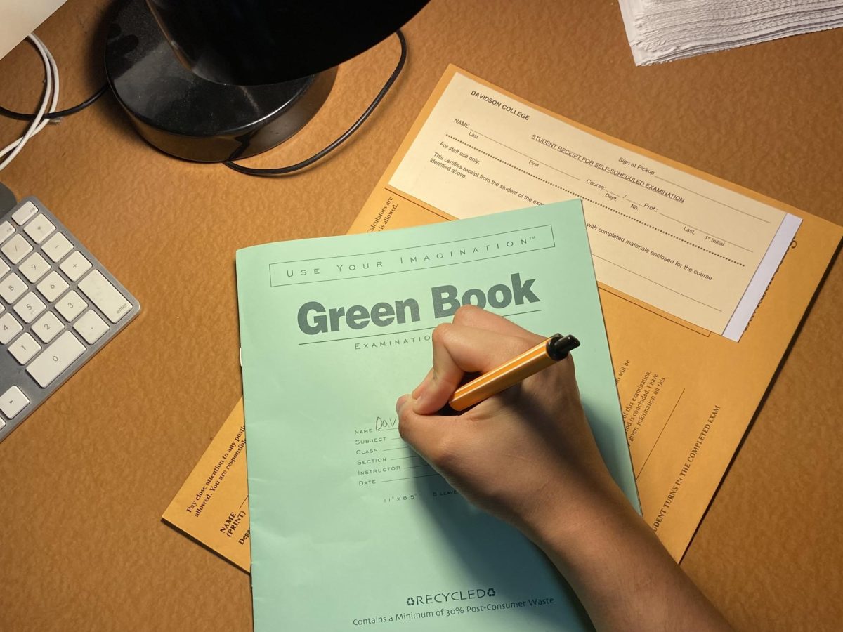 A student uses a green book for an assessment.