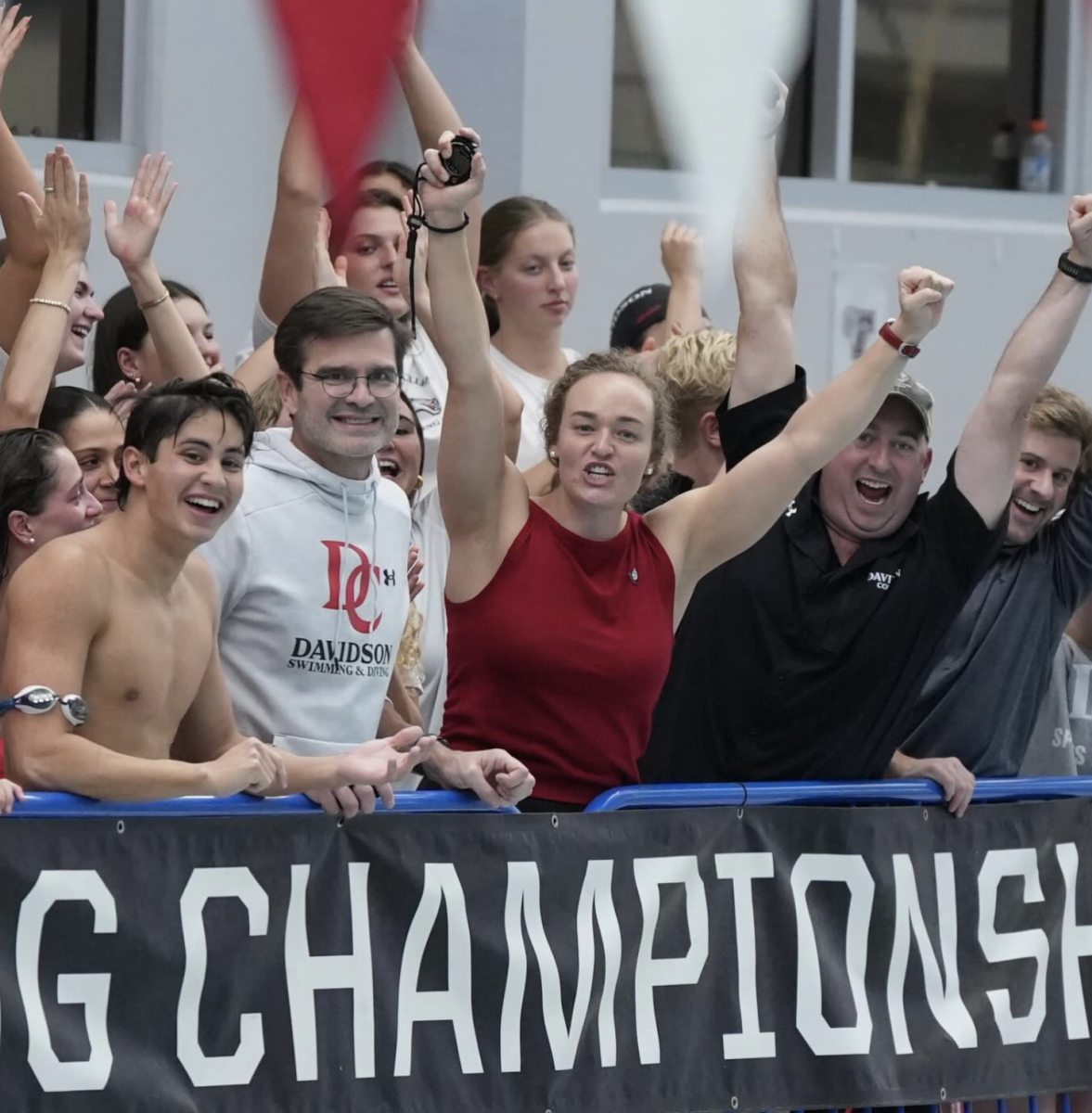 Coaches and swimmers cheer on their teammates. 